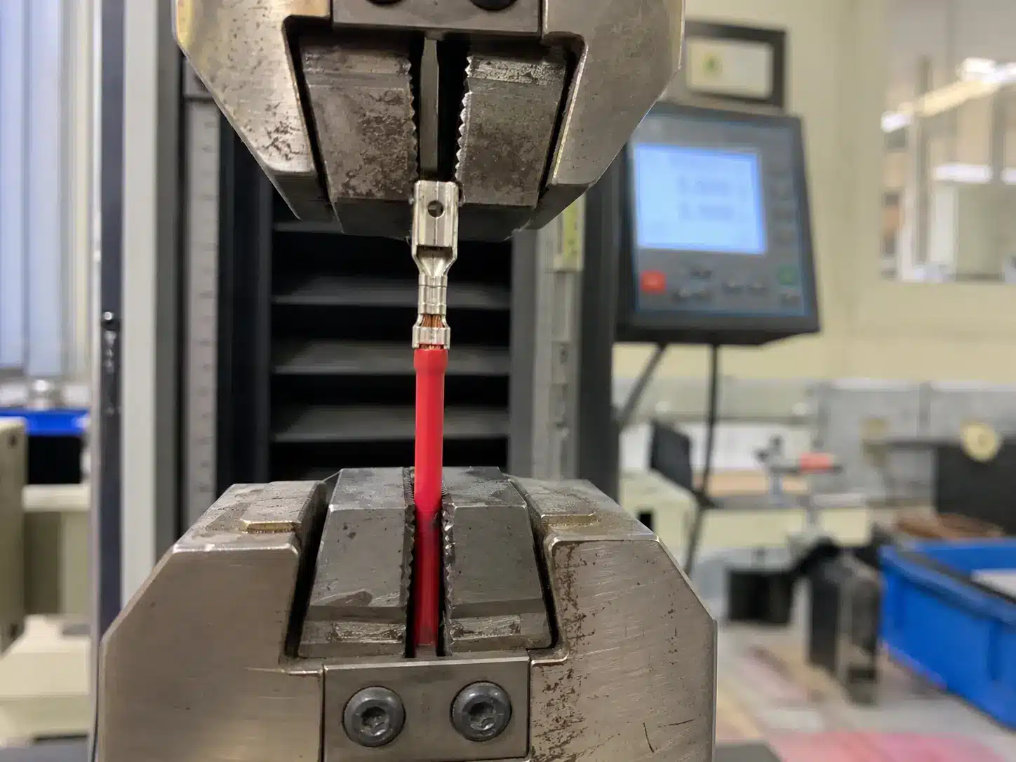 Essai de résistance à la traction sur un échantillon de connecteur serti maintenu dans une machine d'essai de traction