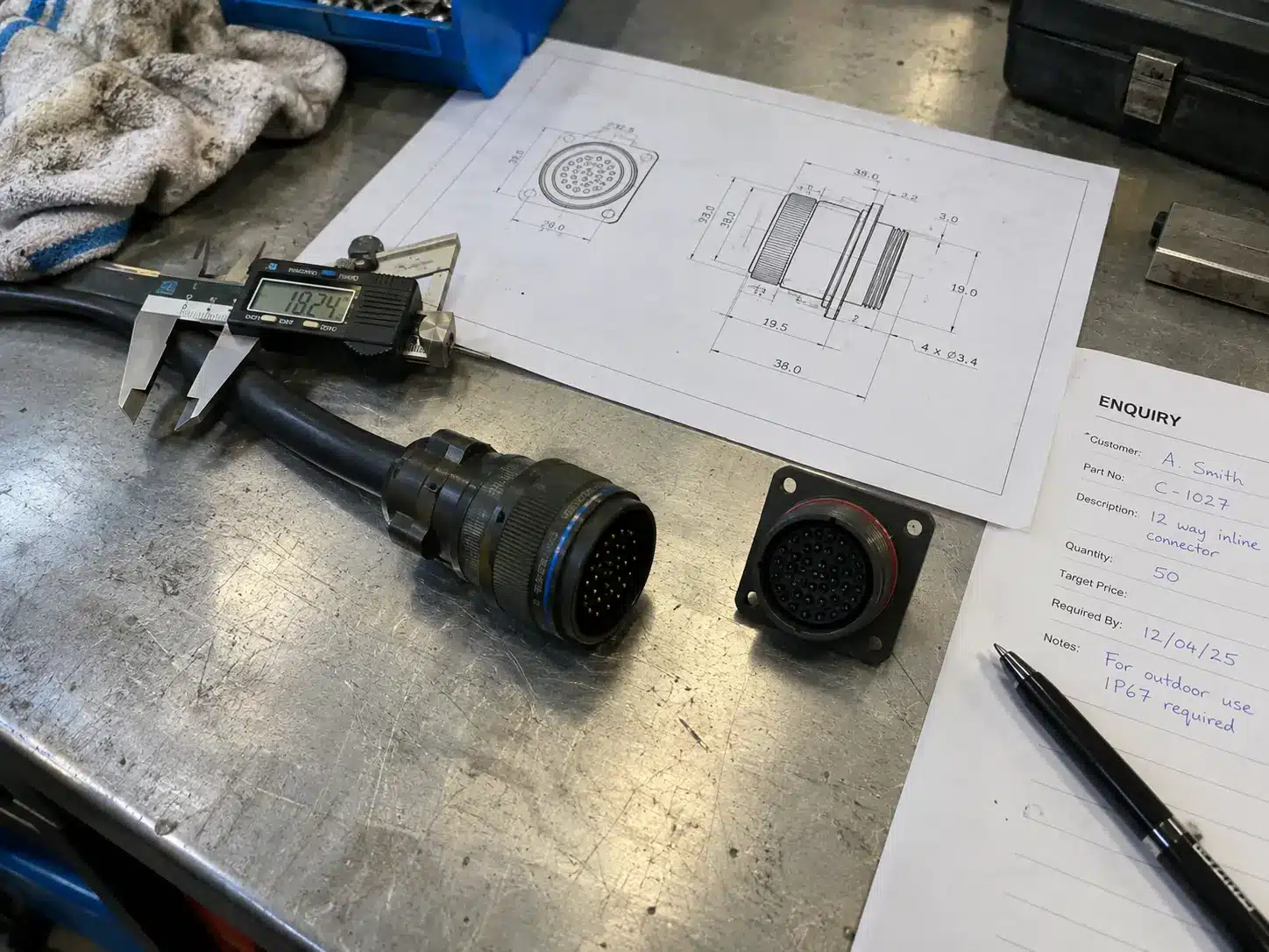 Documents relatifs à une demande de devis pour des connecteurs RF sur un établi : échantillon, demi-connecteur correspondant, plan et pied à coulisse posé sur la gaine du câble