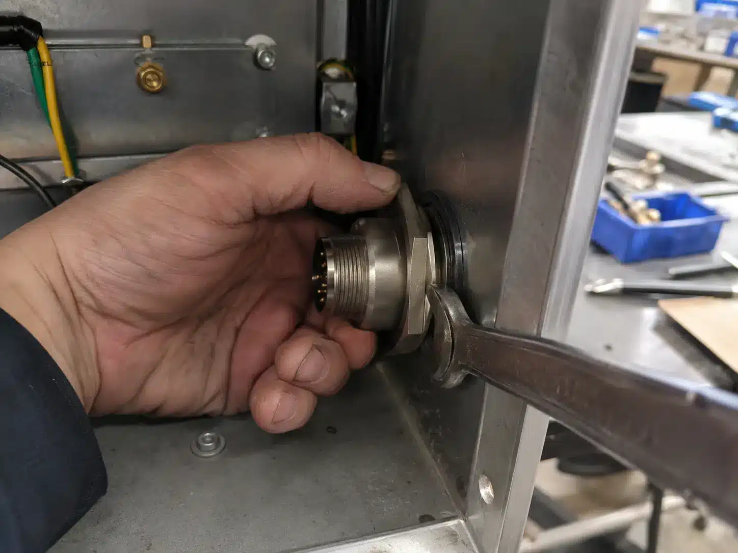 Panel-mount connector being fitted through an enclosure wall with a lock nut